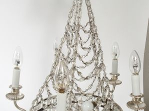 Lustre à quatre lumières à armature en métal nickelé enserrant des chu