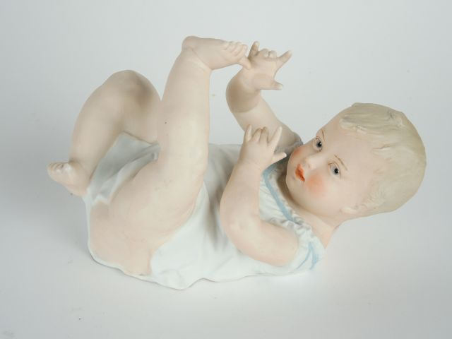 Sujet 1900 en biscuit polychrome 'bébé couché'. 15 x 22,5 cm