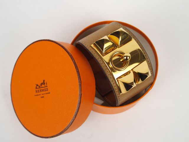 HERMES. Bracelet manchette en métal doré et cuir étoupe, modèle "Médor