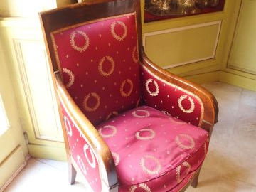 Bergère Empire en noyer, accotoirs stylisés, piètement sabre