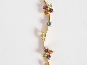 Pendentif monture or jaune parsemé de pierres de couleur formant une t