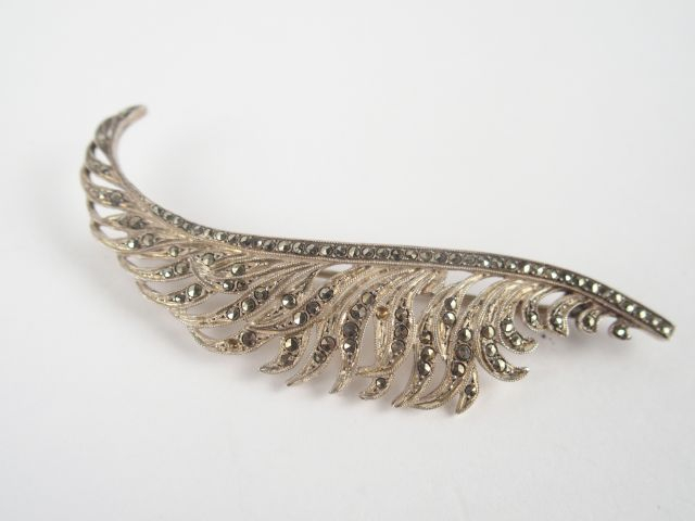 Broche en or blanc en forme de plume, rehaussée de strass. Poids tel: 