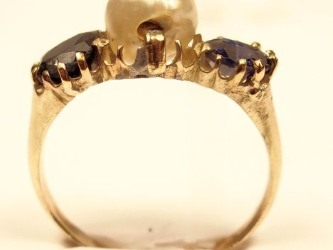 Bague en or jaune, ornée de deux saphirs entourant une perle baroque. 