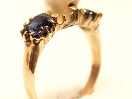 Bague en or jaune, ornée de deux saphirs entourant une perle baroque. 