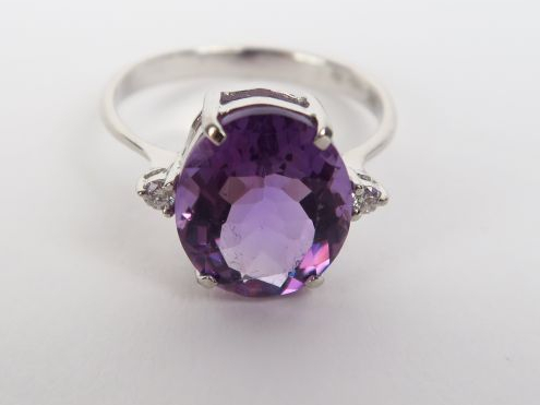 Bague en or gris ornée d'une améthyste, épaulée de deux brillants. Poi
