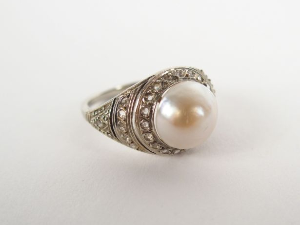 Bague monture platine, pavée de roses et surmontée d'une perle mabée. 