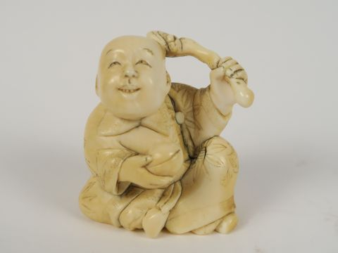 Okimono en ivoire représentant un caraco tenant une pêche et un lingzh