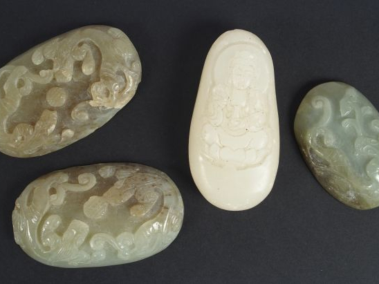 Lot de quatre pendentifs ou éléments en jade ou serpentine, à décor de