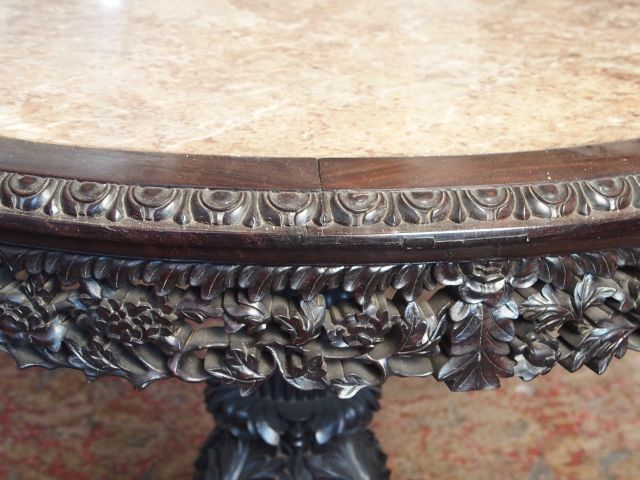 Important guéridon circulaire en bois exotique sculpté, à décor de bra