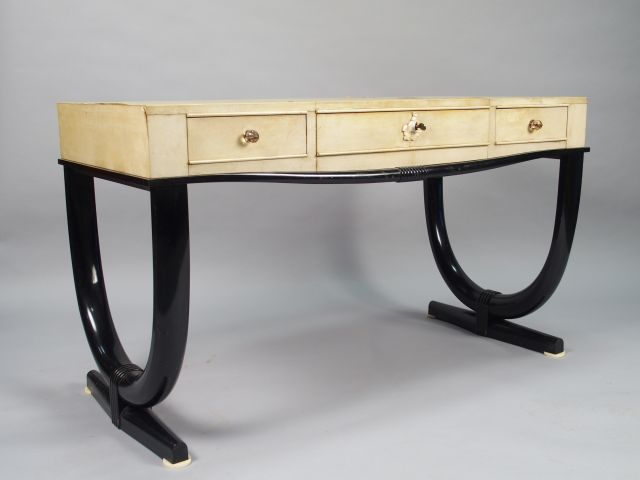André ARBUS. Table bureau en parchemin et laque noire ouvrant à trois 