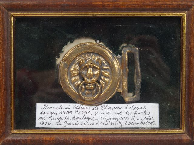 Petit tableau contenant une boucle au masque léonin en bronze et une é