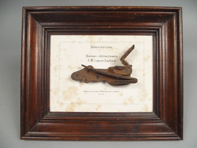 Tableau bois portant en son centre une platine de fusil à la miquelet 