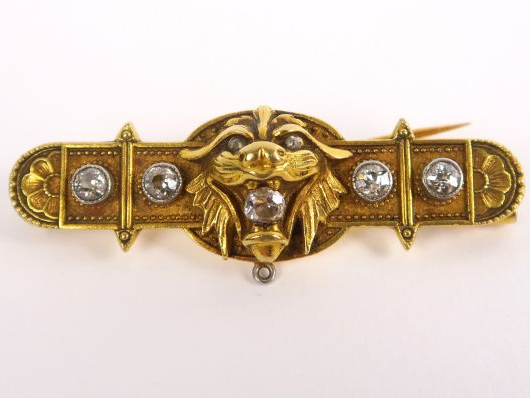 Broche en or à décor de tête de lion, serti de cinq brillants. Poids t