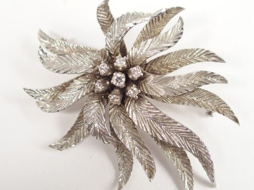 Broche en or blanc en forme de fleur épanouie, rehaussée en son centre