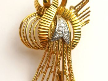 Broche en or figurant un nœud stylisé, rehaussé de petits diamants. Po