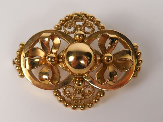 Broche en or jaune à décor de nœuds, perles et entrelacs. Poids : 5,2 