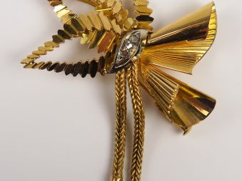 Broche en or deux tons figurant un noeud stylisé, serti de petites ros