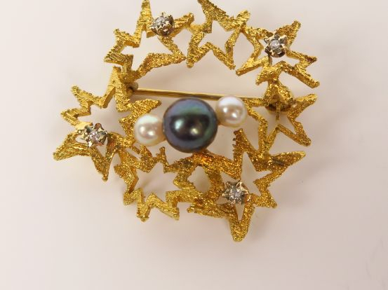 Broche en or à décor d'étoiles stylisées, ornée d'une perle grise épau