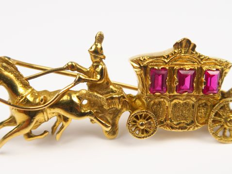 Broche en or en forme de calèche, rehaussé de trois pierres rouges. Po