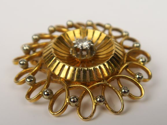 Broche ronde en or à décor d'entrelacs, ornée d'un diamant central et 