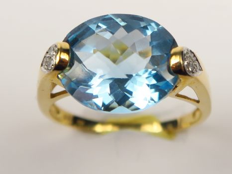 Bague sertie d'une pierre bleue facetée, monture en or ornée de petite
