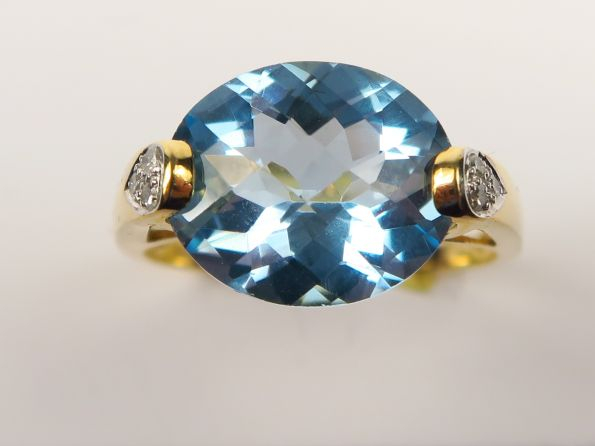 Bague sertie d'une pierre bleue facetée, monture en or ornée de petite