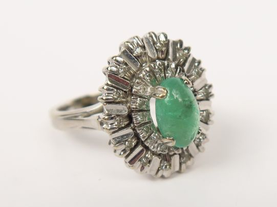 Bague en or gris ornée d’un cabochon d’émeraude sur un décor rayonnant