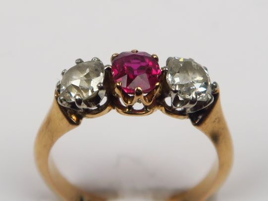 Bague en or ornée d'un rubis épaulé de deux diamants taille ancienne. 