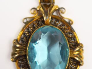 Pendentif en métal doré orné d'une pierre de couleur