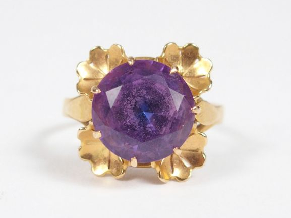 Bague monture or jaune ornée d’un corindon synthétique violet entourag