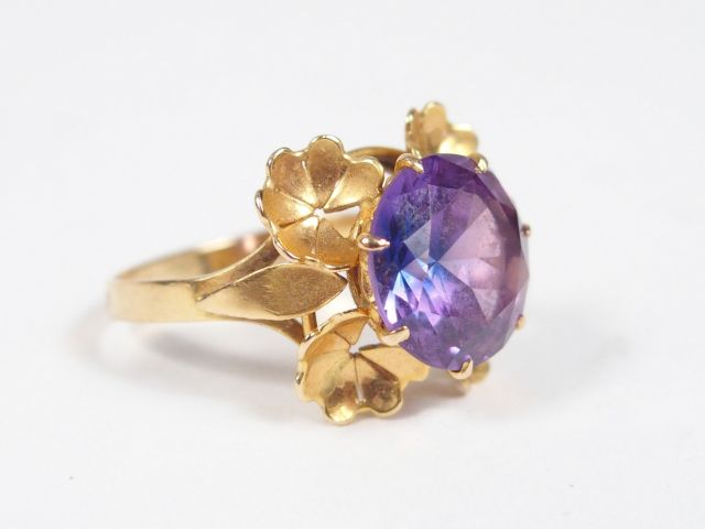 Bague monture or jaune ornée d’un corindon synthétique violet entourag