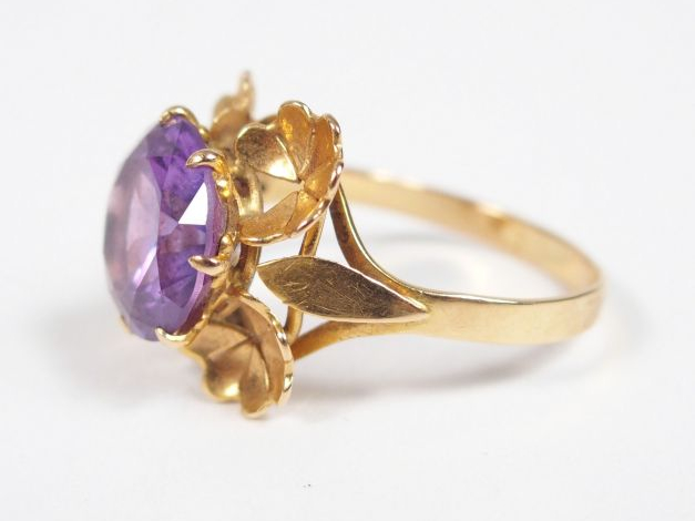 Bague monture or jaune ornée d’un corindon synthétique violet entourag