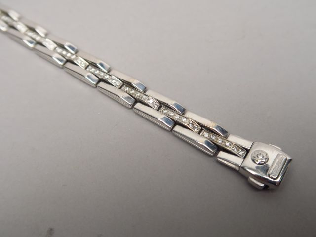 Bracelet articulé en or blanc, orné d'une ligne de brillants. On y joi