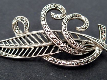 Broche en argent, en forme de plume et de volutes, pavée de strass. 6c