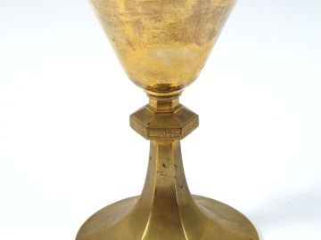 Calice moderne en laiton. Au centre, bague gravée de lettres latines. 