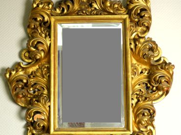 Glace début XIXème de style italien en bois sculpté, doré et ajouré à 