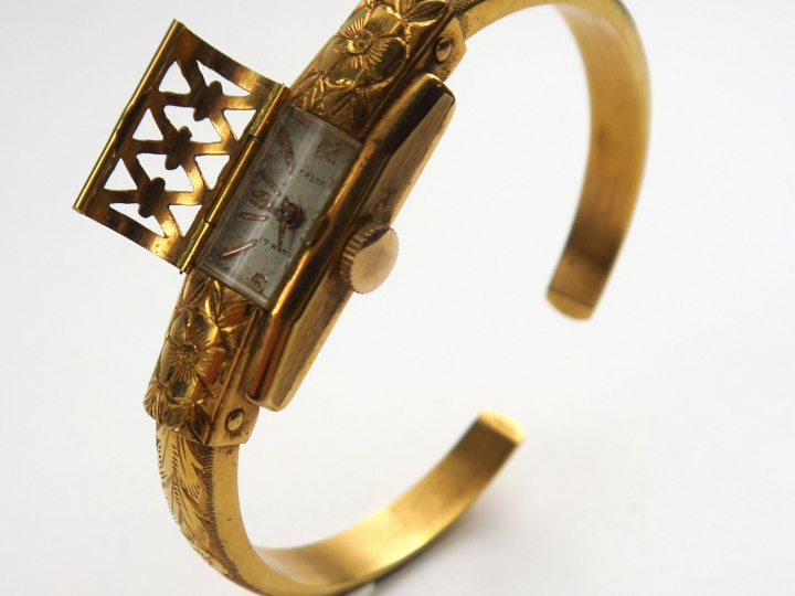 DELRIO. Montre bracelet en or gravé à décor de fleurs, cadran cage. Po