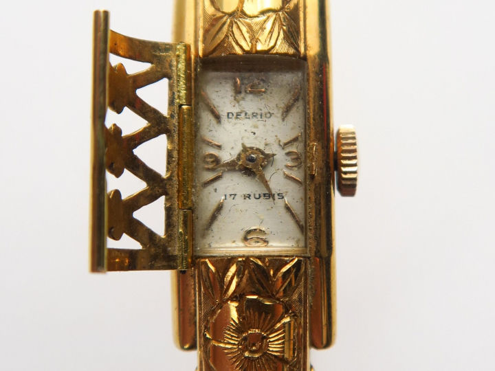 DELRIO. Montre bracelet en or gravé à décor de fleurs, cadran cage. Po