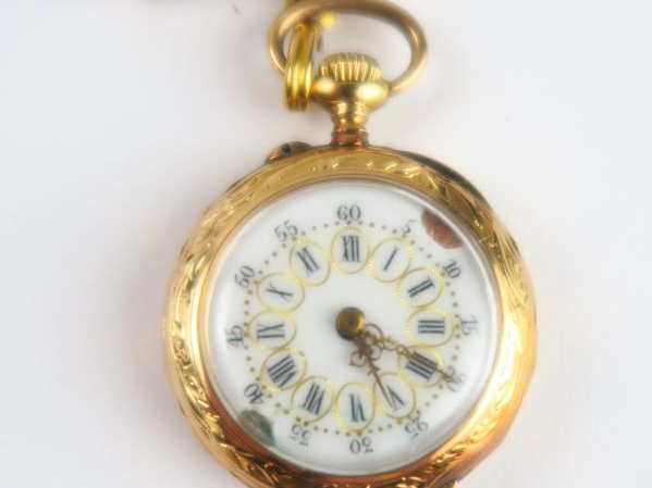 9/ Montre de col en or. Poids tel : 17 g. On y joint une broche en mét