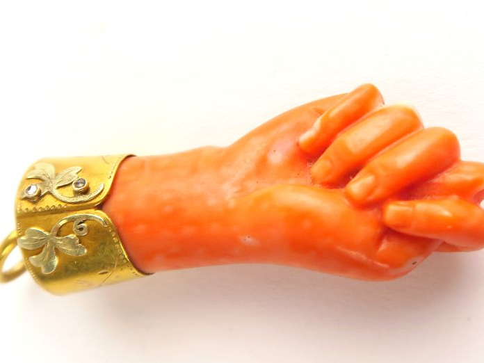 Pendeloque en corail, monture en or, figurant une main. Longueur : 4,5