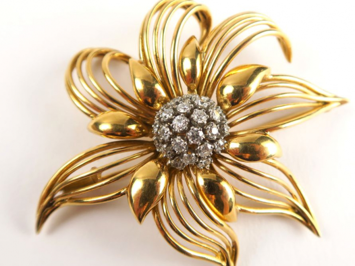 Broche en or, en forme de fleur stylisée, sertie en son centre de diam