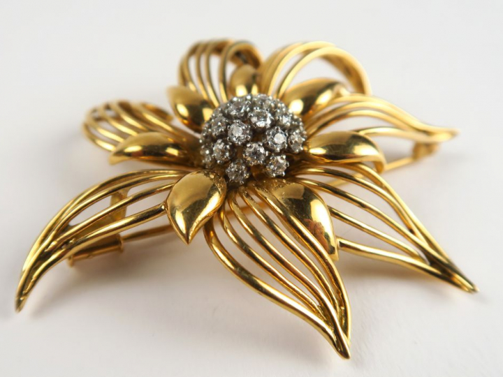 Broche en or, en forme de fleur stylisée, sertie en son centre de diam
