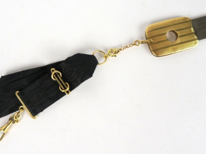 	Coupe-cigarillos en or et métal, sur son lien en soie noire. Poids te