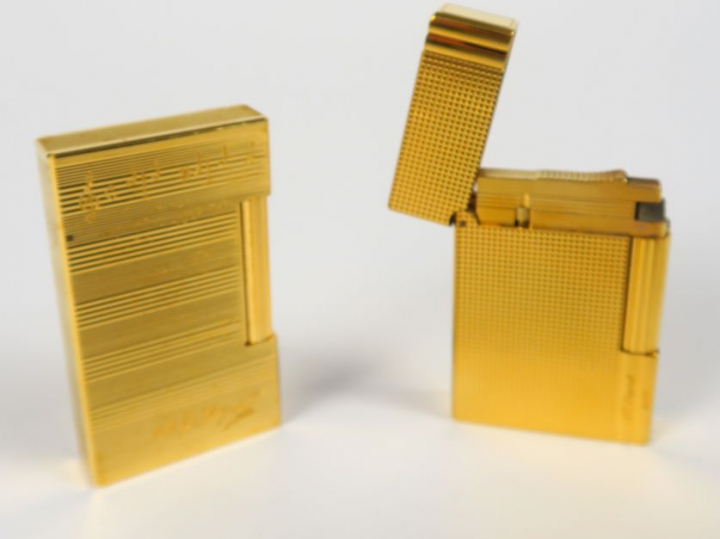 DUPONT. Deux briquets en métal doré, dont un gravé de partitions