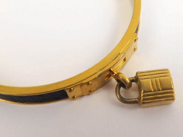 HERMES. Bracelet kelly en métal doré et cuir (usures)