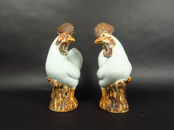 Paire de coqs en porcelaine émaillée blanc et brun, debout sur des roc