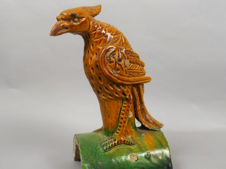 Tuile faitière en céramique émaillée ocre et vert, représentant un phé