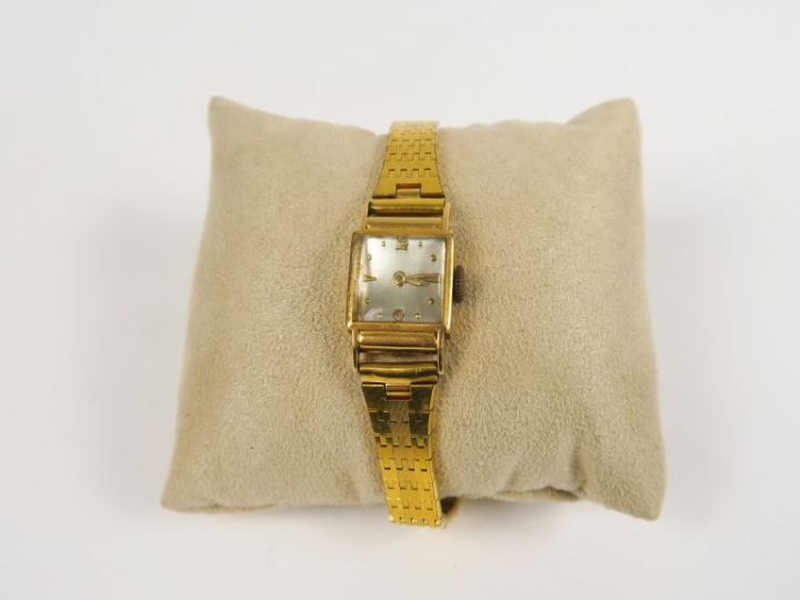 Montre de dame boitier or jaune, bracelet articulé en métal doré.