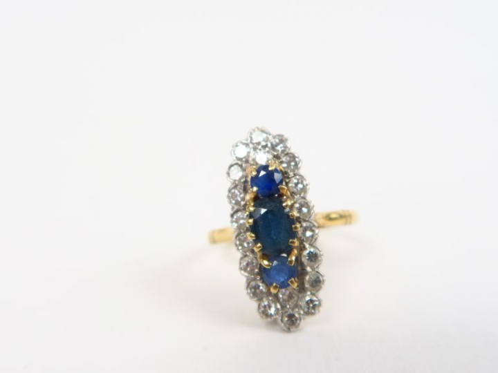 Bague marquise en or ornée de trois saphirs et entourage de petits bri