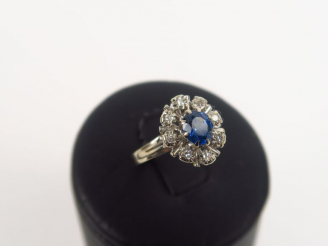 Vente aux enchères Bague marguerite monture or blanc, ornée d'un saphir entouré de huit b